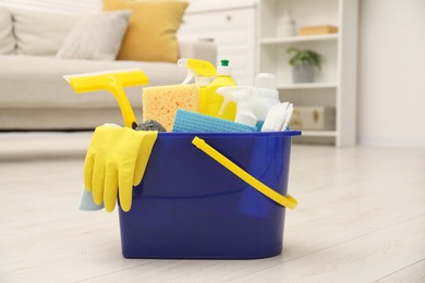 Photo of Different cleaning supplies in bucket on floor at home