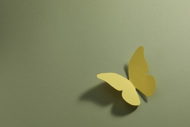 Photo of Yellow paper butterfly on pale green background, top view. Space for text