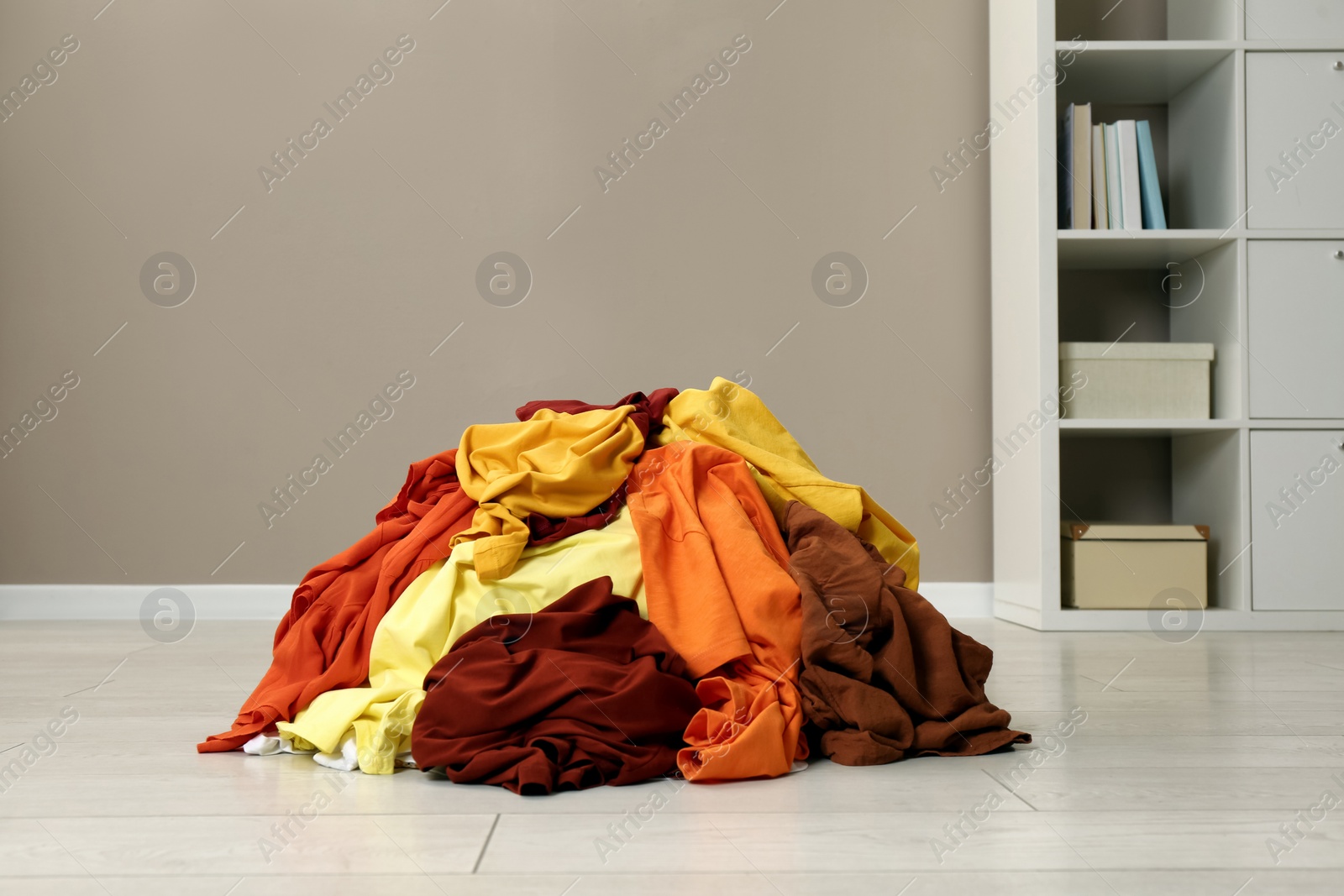 Photo of Pile of dirty clothes on floor near light brown wall indoors