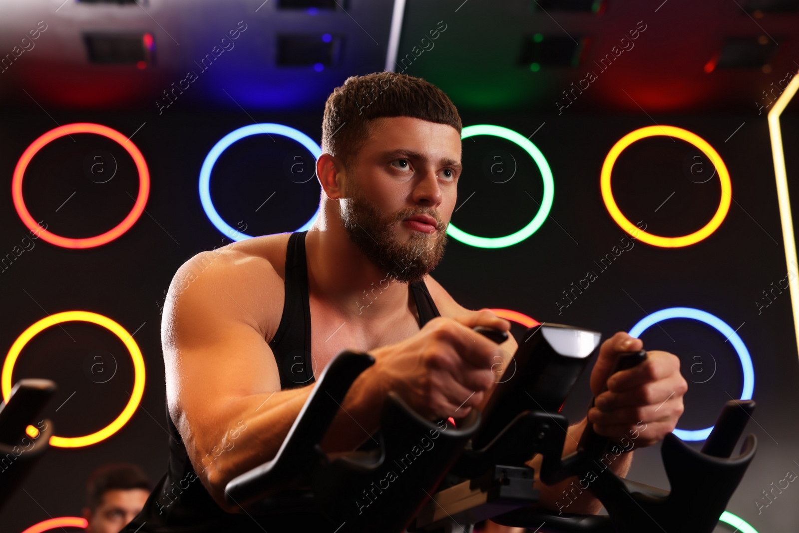 Photo of Young man training on exercise bike in fitness club