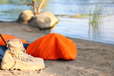 Sleeping bag and boots on beach near lake