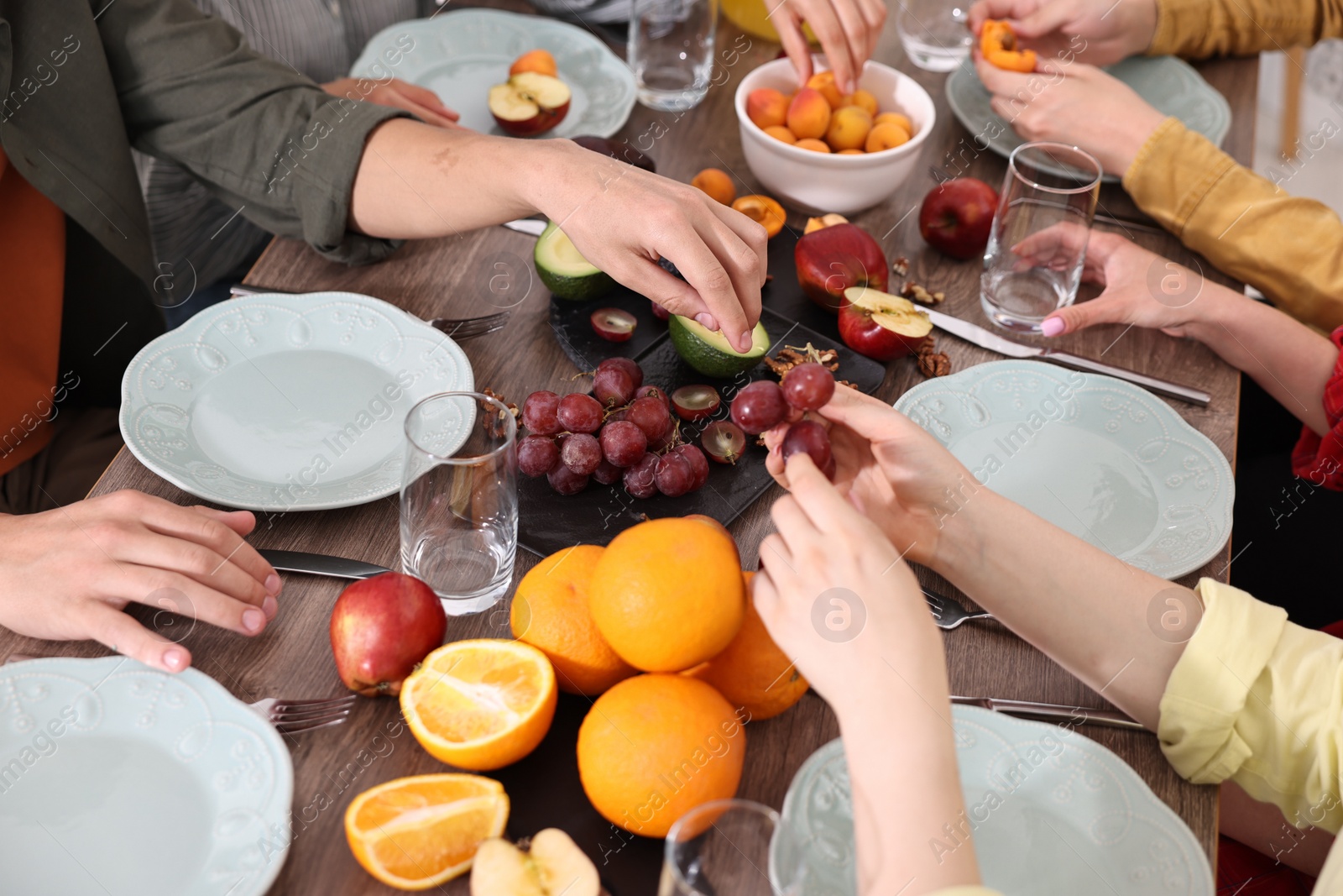 Photo of Friends eating vegetarian food at wooden table indoors, closeup