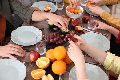 Photo of Friends eating vegetarian food at wooden table indoors, closeup