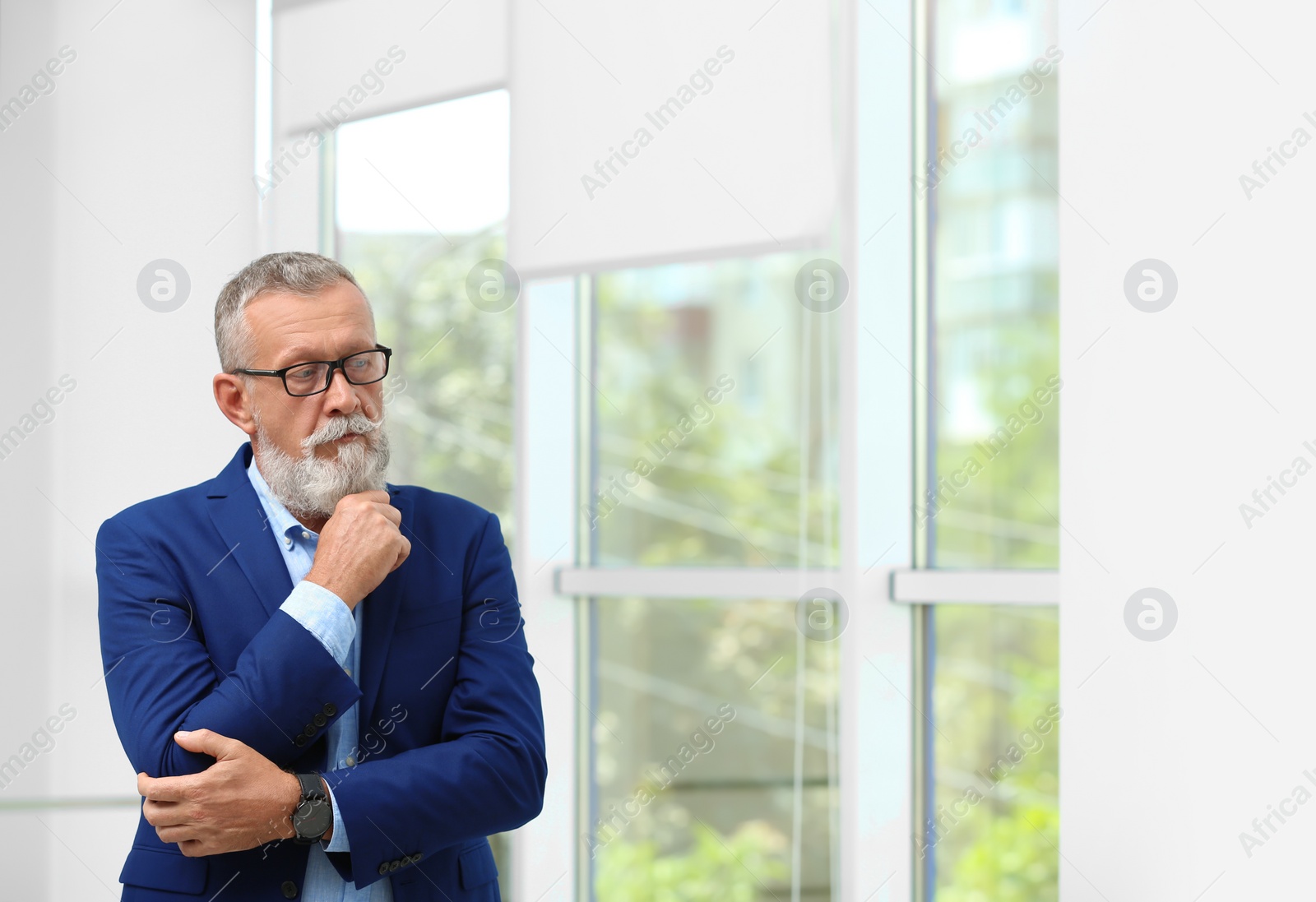 Photo of Portrait of handsome mature man in elegant suit with glasses indoors