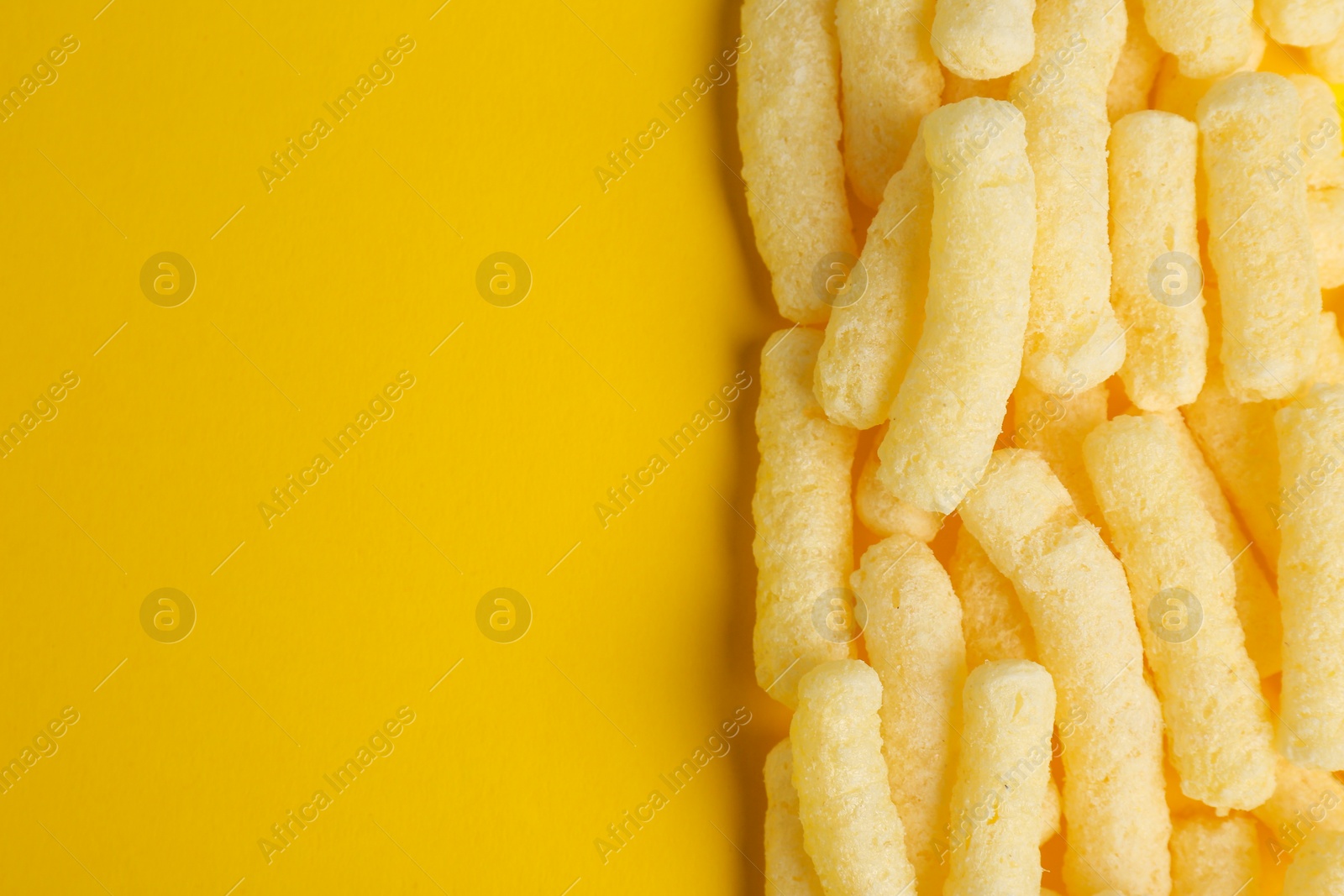 Photo of Tasty corn sticks on yellow background, top view. Space for text