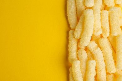 Photo of Tasty corn sticks on yellow background, top view. Space for text