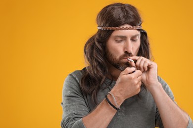 Photo of Hippie man lighting cigarette on orange background