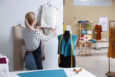 Photo of Dressmaker working in modern atelier, back view