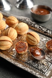 Photo of Homemade walnut shaped cookies with boiled condensed milk on grey table, closeup