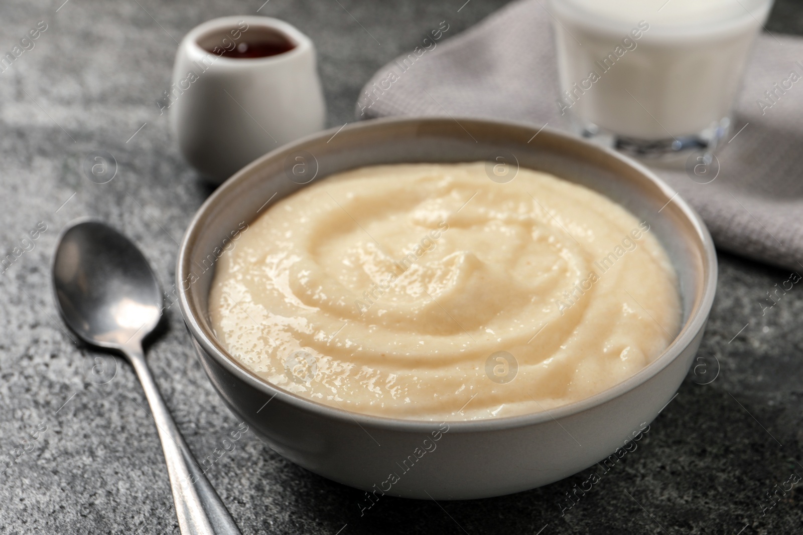 Photo of Bowl with delicious semolina pudding on grey table