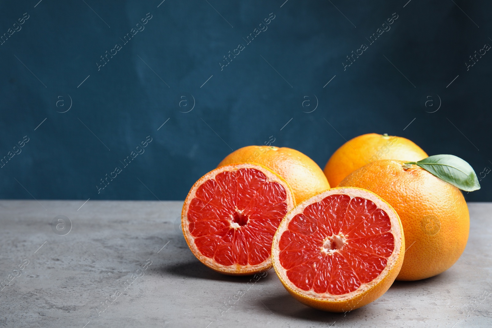 Photo of Fresh tasty grapefruits on table against color background. Space for text