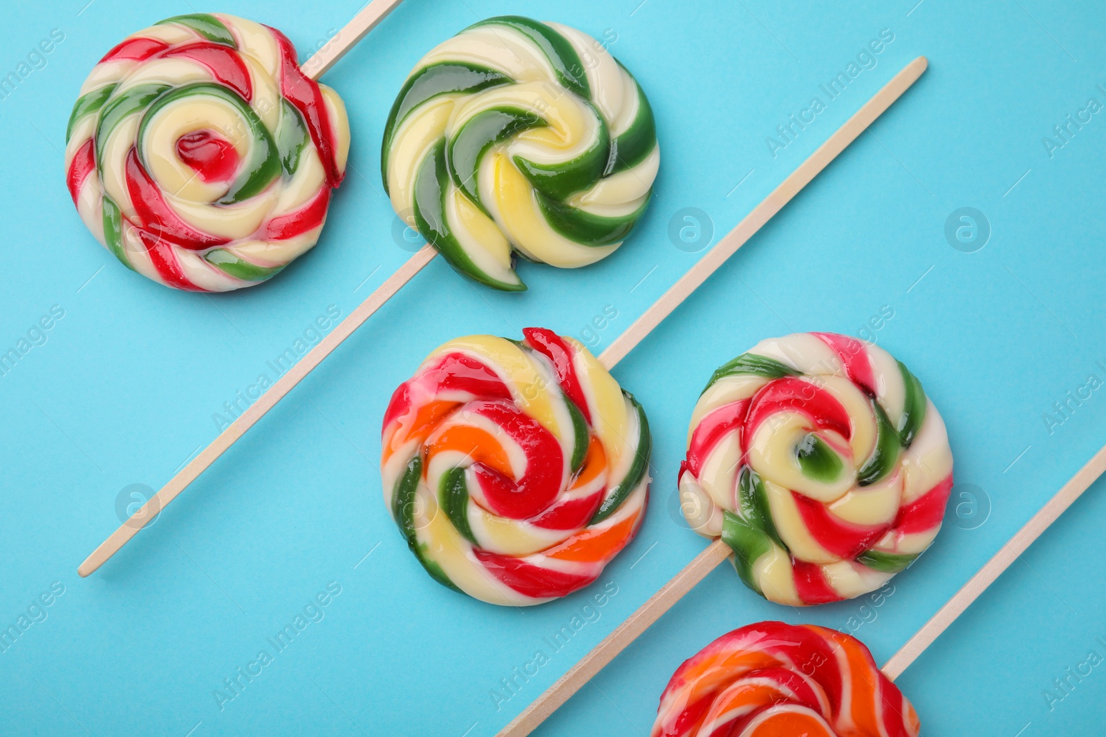 Photo of Many colorful lollipops on light blue background, flat lay