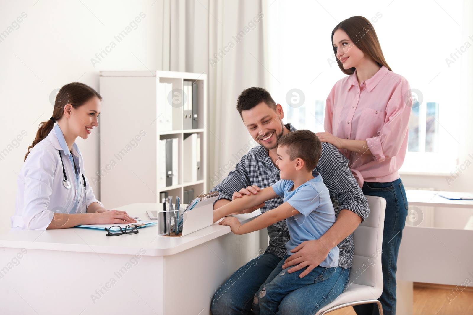 Photo of Parents and son visiting pediatrician. Doctor working with patient in hospital