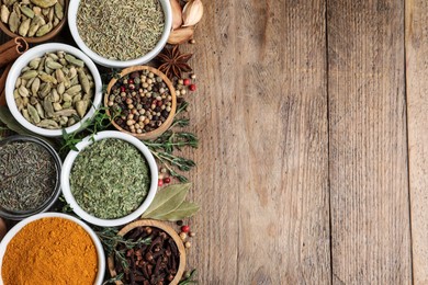 Flat lay composition with different natural spices and herbs on wooden table, space for text