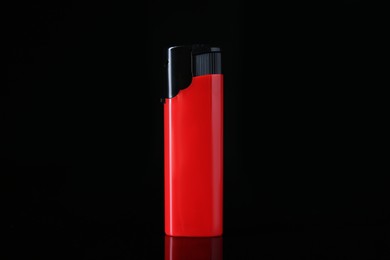 Photo of Red plastic cigarette lighter on black background, closeup