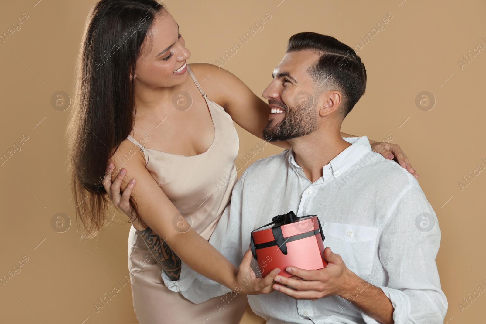 Photo of Lovely couple with gift on beige background