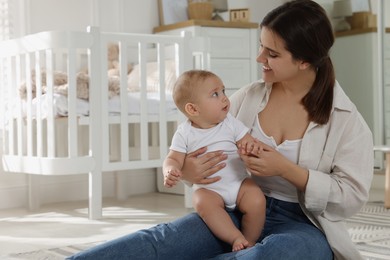 Photo of Happy young mother with her baby in nursery. Space for text