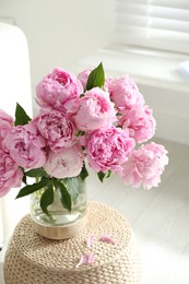 Bouquet of beautiful peonies on pouf indoors