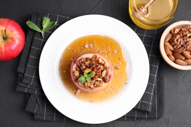 Photo of Tasty baked apple with nuts, honey and mint on gray textured table, flat lay