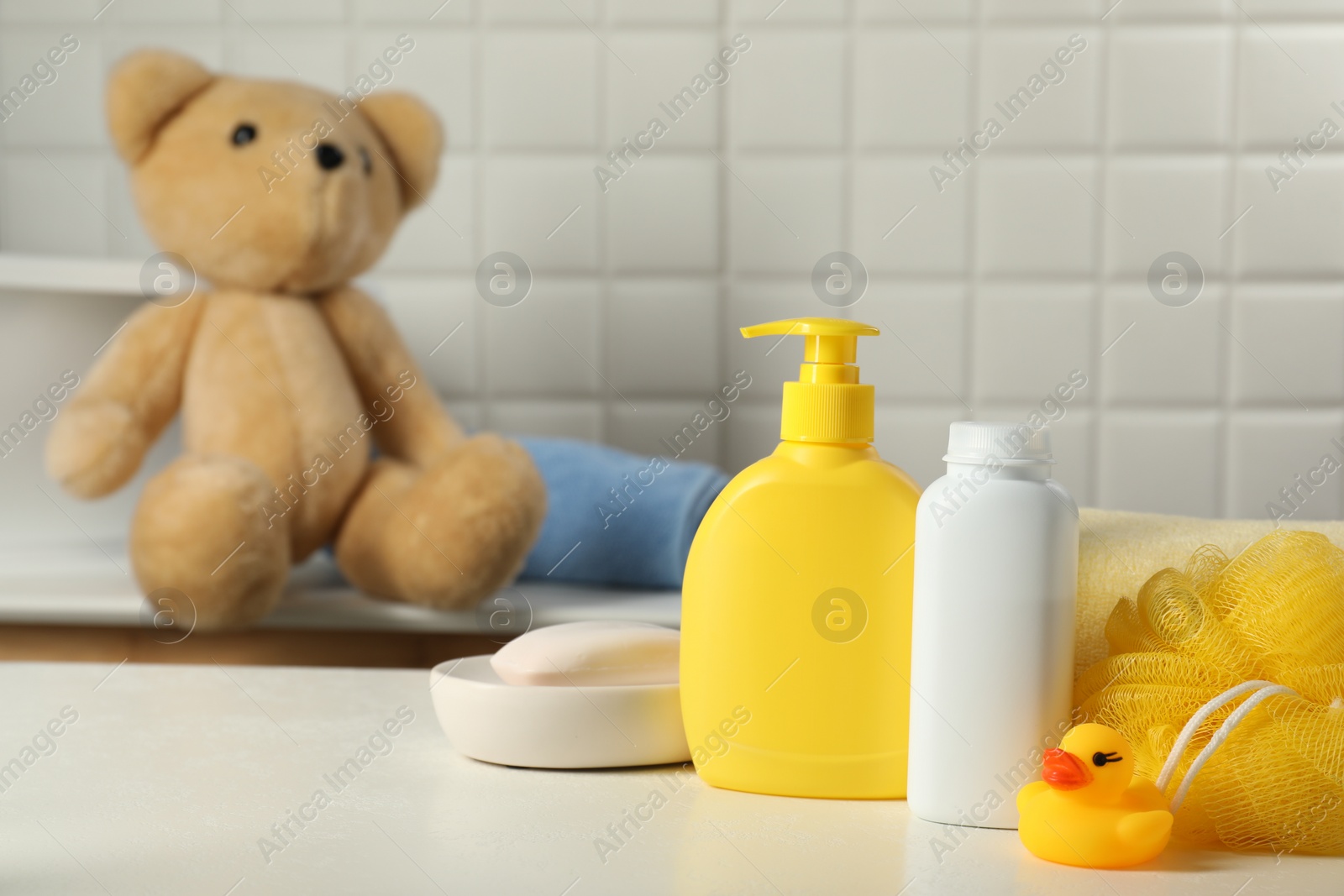 Photo of Baby cosmetic products, bath duck and sponge on white table indoors. Space for text