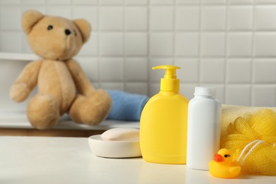 Baby cosmetic products, bath duck and sponge on white table indoors. Space for text