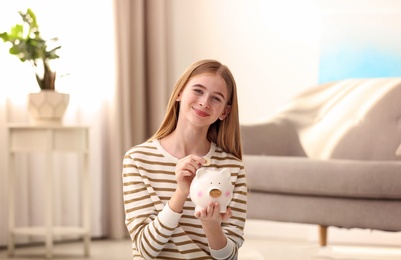 Teen girl with piggy bank and money at home