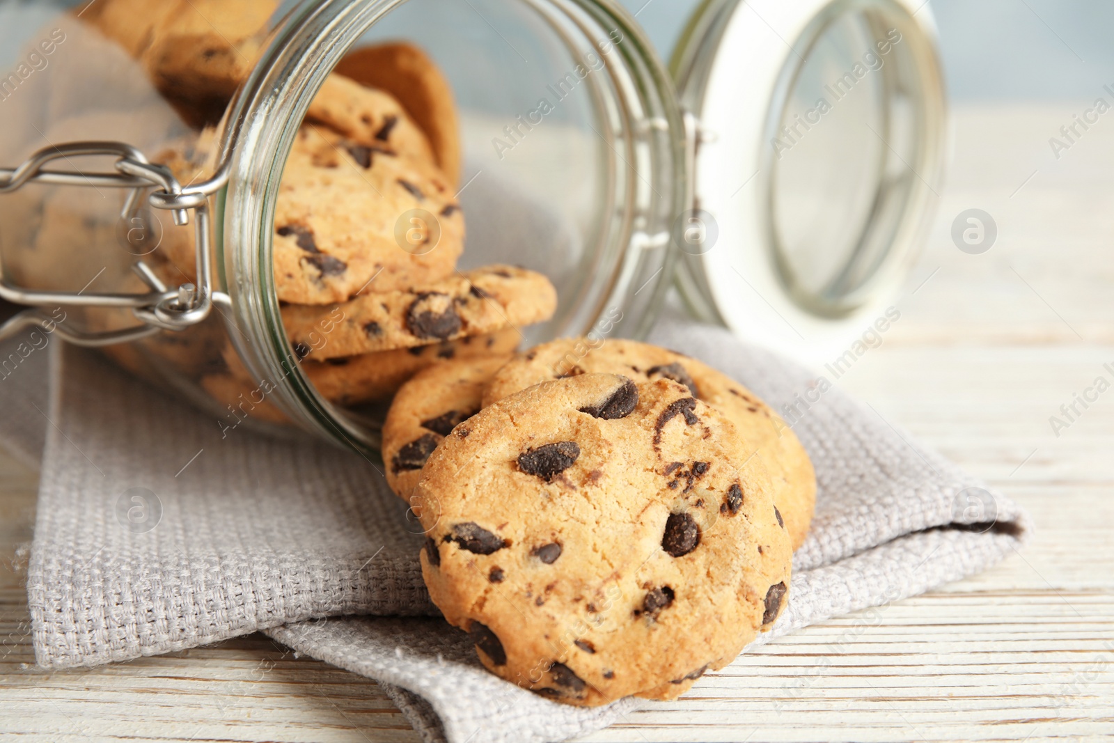 Photo of Jar of tasty chocolate chip cookies on wooden background