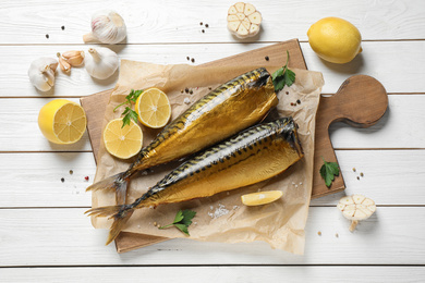 Flat lay composition with tasty smoked fish on white wooden table