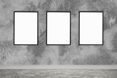 Image of Frames with empty canvases on grey wall in modern art gallery. Space for design