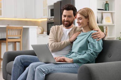 Photo of Happy couple with laptop on sofa at home