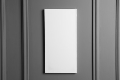 Photo of Blank canvas hanging on grey wall, space for text