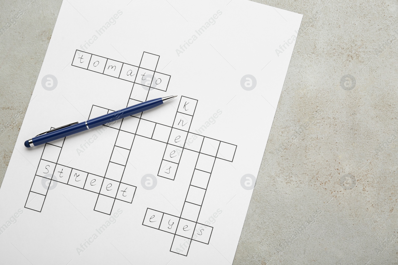 Photo of Crossword with answers and pen on old white table, top view. Space for text