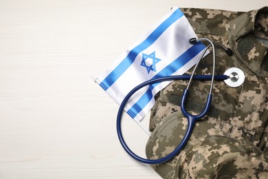 Photo of Stethoscope, flag of Israel and military uniform on white wooden table, top view. Space for text
