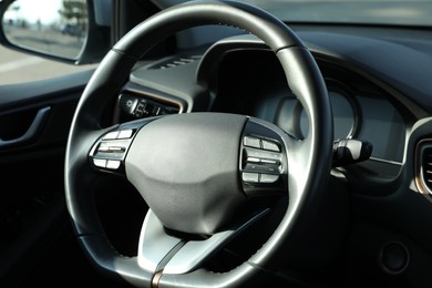 Photo of Black steering wheel inside of modern car, closeup