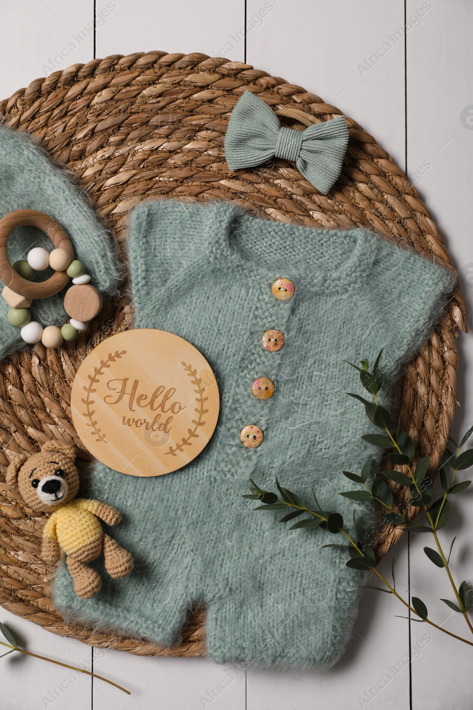 Photo of Children's clothes, toys and green plant on white wooden table, top view