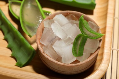 Photo of Aloe vera gel and slices of plant on bamboo mat, closeup