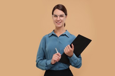 Photo of Young secretary with clipboard and pen on beige background