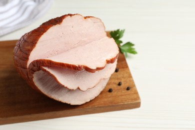 Photo of Delicious cut ham with board, parsley and peppercorns on white wooden table, closeup
