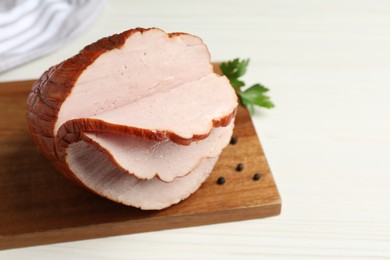 Delicious cut ham with board, parsley and peppercorns on white wooden table, closeup