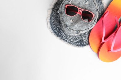 Photo of Sunglasses, hat and bright flip flops on white background, flat lay with space for text. Beach accessories