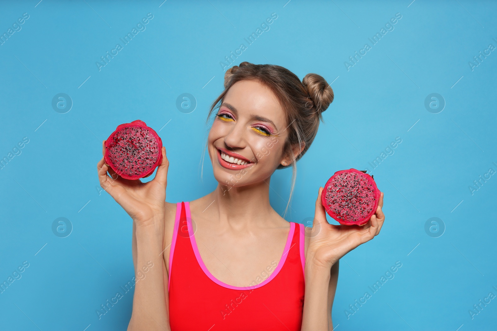 Photo of Young woman with fresh pitahaya on light blue background. Exotic fruit