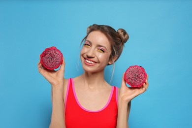 Young woman with fresh pitahaya on light blue background. Exotic fruit