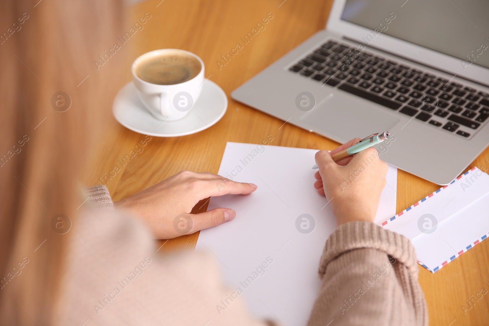 Photo of Woman writing letter at wooden table, closeup