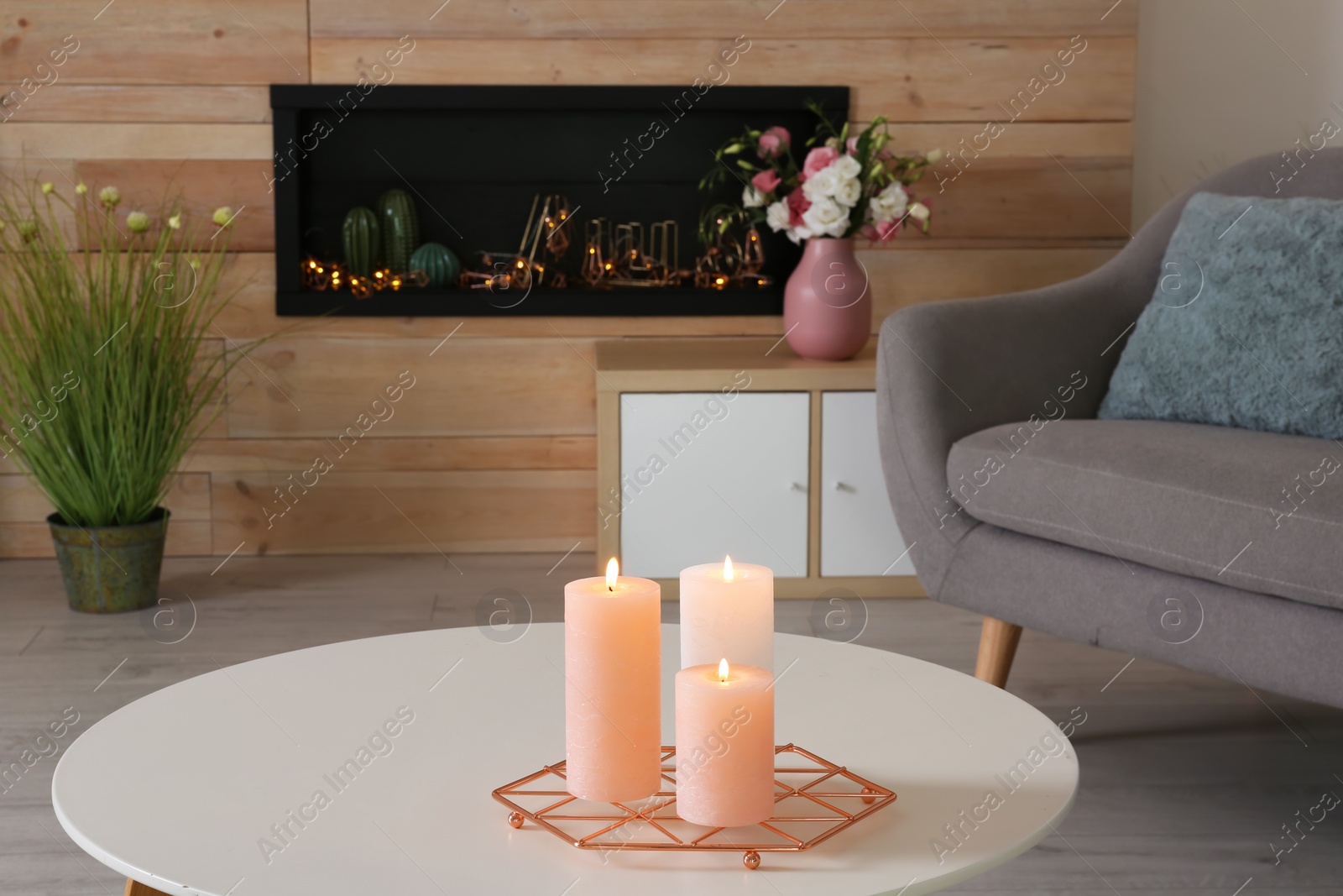 Photo of Burning candles on table in living room