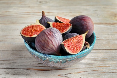 Photo of Bowl with fresh ripe figs on wooden background. Tropical fruit