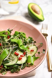 Salad with fresh organic microgreen in bowl on white table, closeup