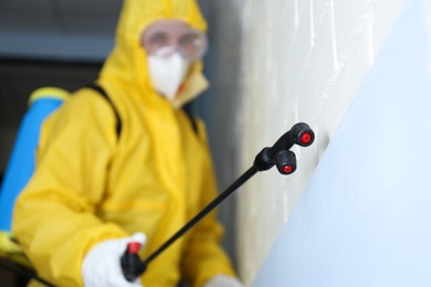 Photo of Pest control worker spraying pesticide indoors, focus on nozzle