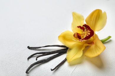 Photo of Beautiful vanilla flower and sticks on light background