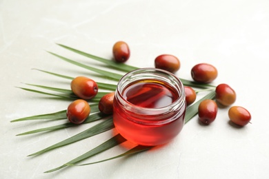 Palm oil in glass jar, tropical leaf and fruits on light table