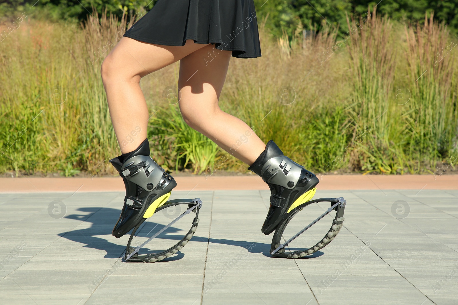 Photo of Woman doing exercises in kangoo jumping boots outdoors, closeup